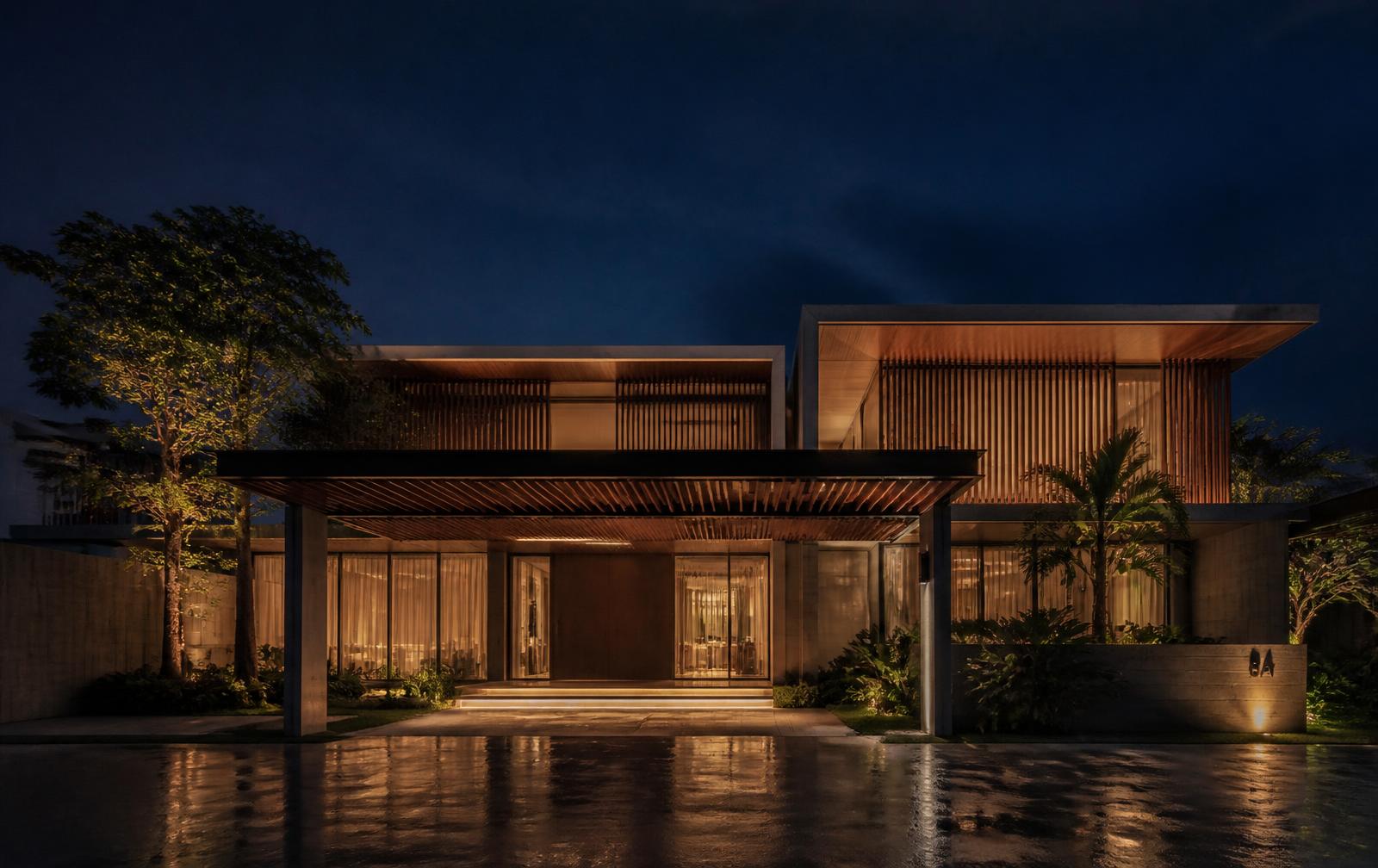 Modern tropical bungalow at dusk with warm interior lighting visible through full-height glazing