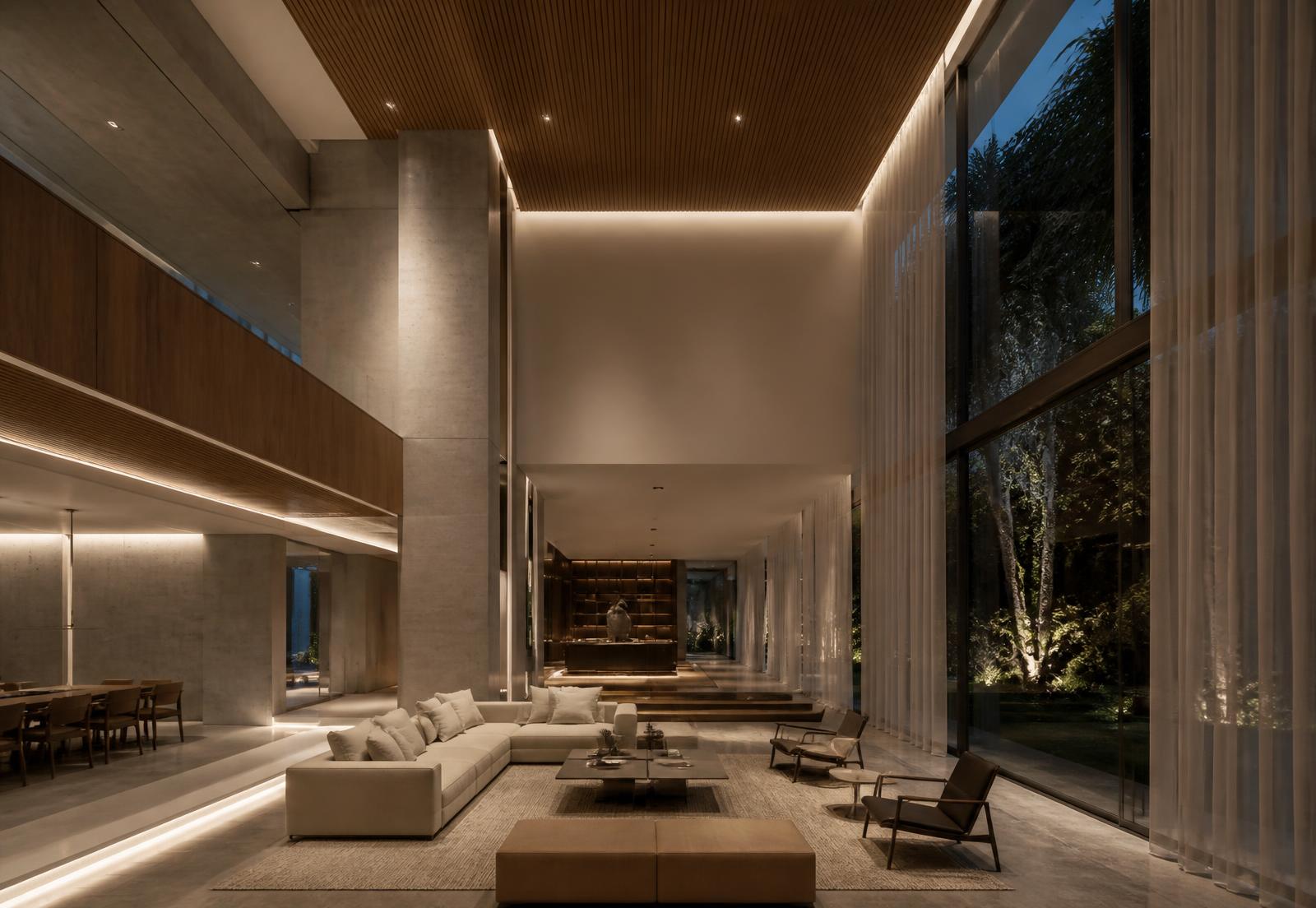 Triple-height living space in a large modern residence with layered architectural lighting at night